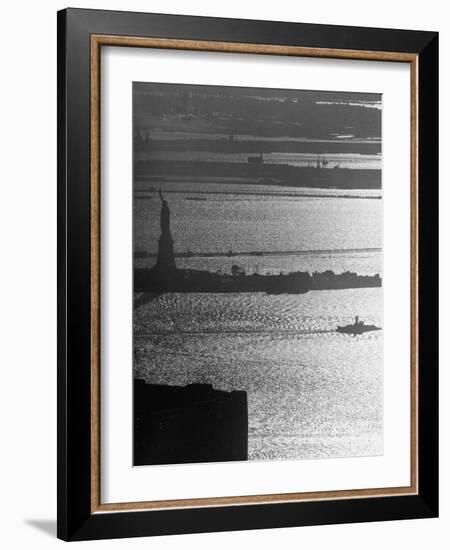 Moonlight on the Waters Surrounding Statue of Liberty as a Tug Boat Steams Past in New York Harbor-Andreas Feininger-Framed Photographic Print