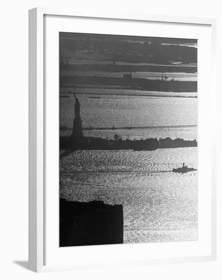 Moonlight on the Waters Surrounding Statue of Liberty as a Tug Boat Steams Past in New York Harbor-Andreas Feininger-Framed Photographic Print