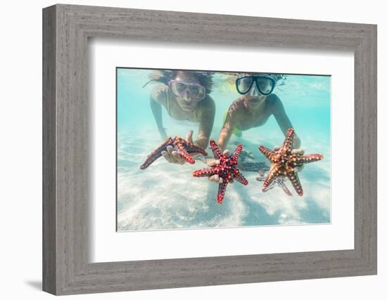 Mother and son with scuba masks showing red starfish underwater, Zanzibar, Tanzania-Roberto Moiola-Framed Photographic Print