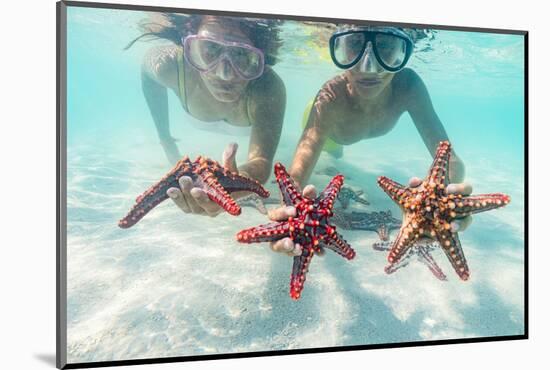 Mother and son with scuba masks showing red starfish underwater, Zanzibar, Tanzania-Roberto Moiola-Mounted Photographic Print