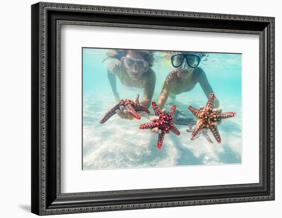 Mother and son with scuba masks showing red starfish underwater, Zanzibar, Tanzania-Roberto Moiola-Framed Photographic Print