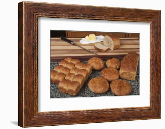 Multigrain rolls, buns and loaf with a slice cut off, with butter and a bread knife.-Janet Horton-Framed Photographic Print