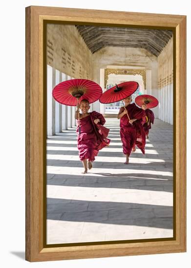 Myanmar, Mandalay Division, Bagan. Three Novice Monks Running with Red Umbrellas in a Walkway (Mr)-Matteo Colombo-Framed Premier Image Canvas