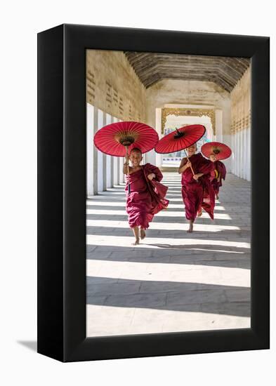Myanmar, Mandalay Division, Bagan. Three Novice Monks Running with Red Umbrellas in a Walkway (Mr)-Matteo Colombo-Framed Premier Image Canvas