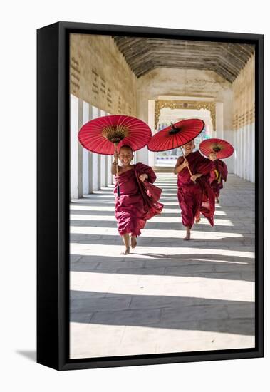 Myanmar, Mandalay Division, Bagan. Three Novice Monks Running with Red Umbrellas in a Walkway (Mr)-Matteo Colombo-Framed Premier Image Canvas
