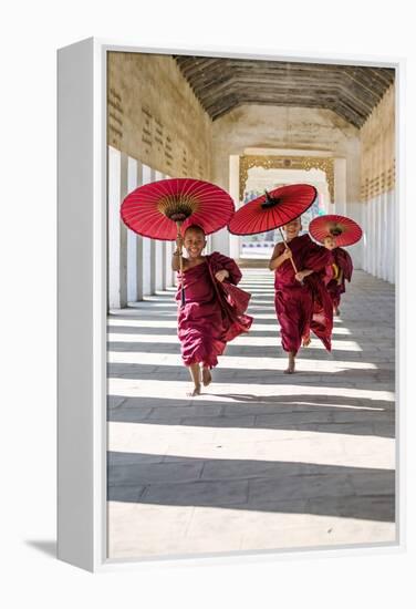 Myanmar, Mandalay Division, Bagan. Three Novice Monks Running with Red Umbrellas in a Walkway (Mr)-Matteo Colombo-Framed Premier Image Canvas