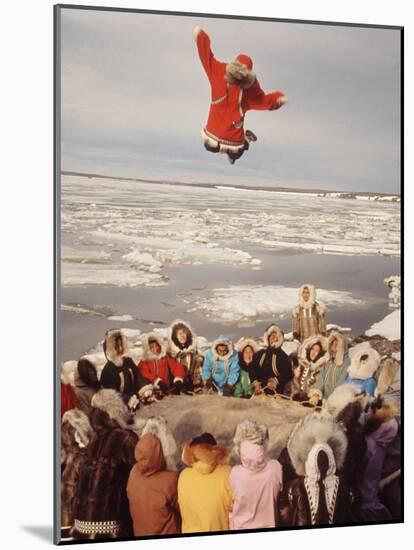 Native Alaskans Playing a Game of Nulukatuk, in Which Individals are Tossed into the Air-Ralph Crane-Mounted Photographic Print