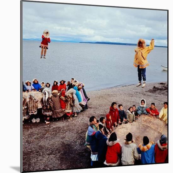 Native Alaskans Playing a Game of Nulukatuk, in Which Individals are Tossed into the Air-Ralph Crane-Mounted Photographic Print