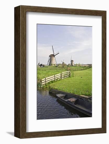 Netherlands, Kinderdijk. Windmills and boat next to canal.-Jaynes Gallery-Framed Photographic Print