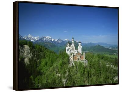 Neuschwanstein Castle on a Wooded Hill with Mountains in the