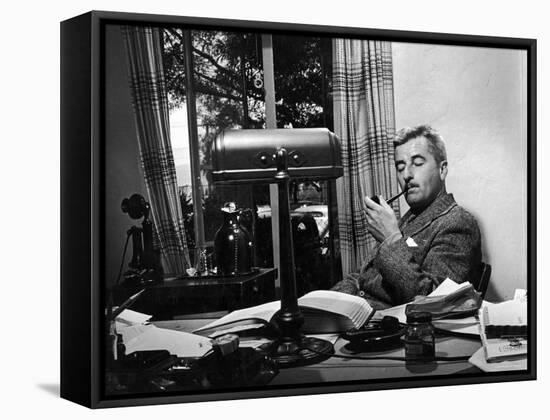 Novelist and Script Writer William Faulkner Smoking a Pipe at His Desk at Warner Brothers Studios-null-Framed Premier Image Canvas