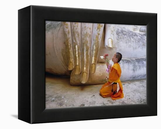 Novice Buddhist Monk Kneeling Beneath the Phra Atchana Buddha Statue, Sukhothai Province, Thailand-Gavin Hellier-Framed Premier Image Canvas