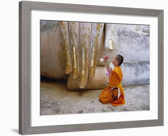 Novice Buddhist Monk Kneeling Beneath the Phra Atchana Buddha Statue, Sukhothai Province, Thailand-Gavin Hellier-Framed Photographic Print