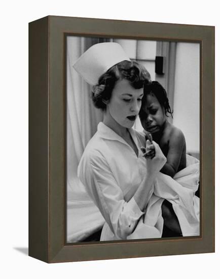 Nurse Holding African American Girl in Her Arms, Examining Her Finger-John Dominis-Framed Premier Image Canvas