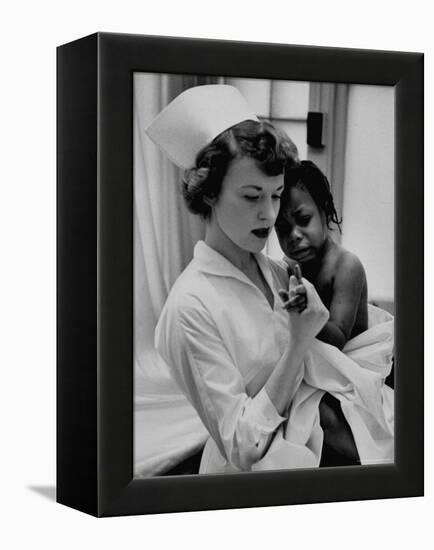 Nurse Holding African American Girl in Her Arms, Examining Her Finger-John Dominis-Framed Premier Image Canvas