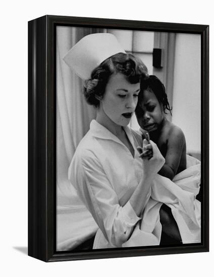 Nurse Holding African American Girl in Her Arms, Examining Her Finger-John Dominis-Framed Premier Image Canvas