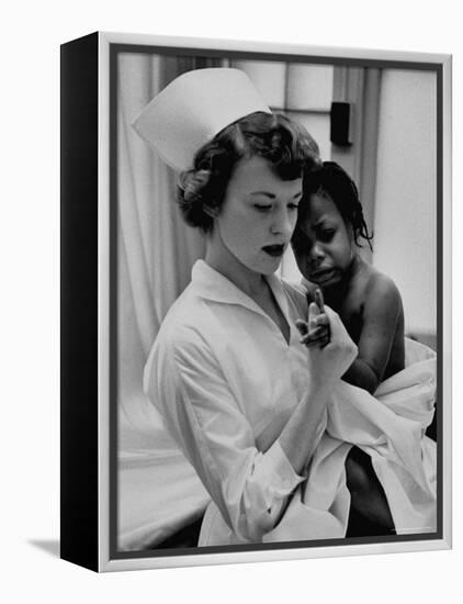 Nurse Holding African American Girl in Her Arms, Examining Her Finger-John Dominis-Framed Premier Image Canvas