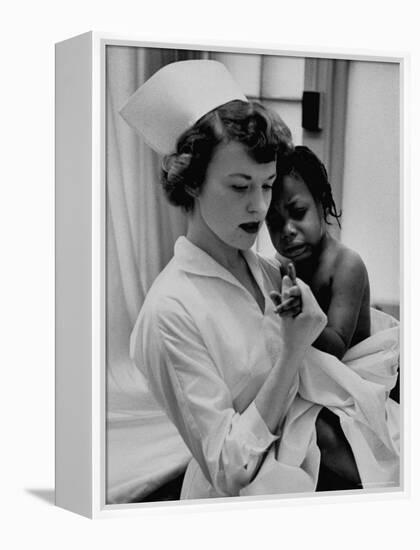 Nurse Holding African American Girl in Her Arms, Examining Her Finger-John Dominis-Framed Premier Image Canvas