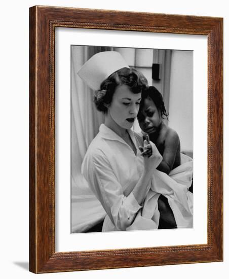 Nurse Holding African American Girl in Her Arms, Examining Her Finger-John Dominis-Framed Photographic Print