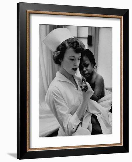 Nurse Holding African American Girl in Her Arms, Examining Her Finger-John Dominis-Framed Photographic Print