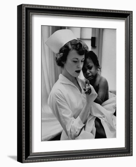 Nurse Holding African American Girl in Her Arms, Examining Her Finger-John Dominis-Framed Photographic Print