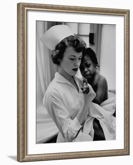 Nurse Holding African American Girl in Her Arms, Examining Her Finger-John Dominis-Framed Photographic Print