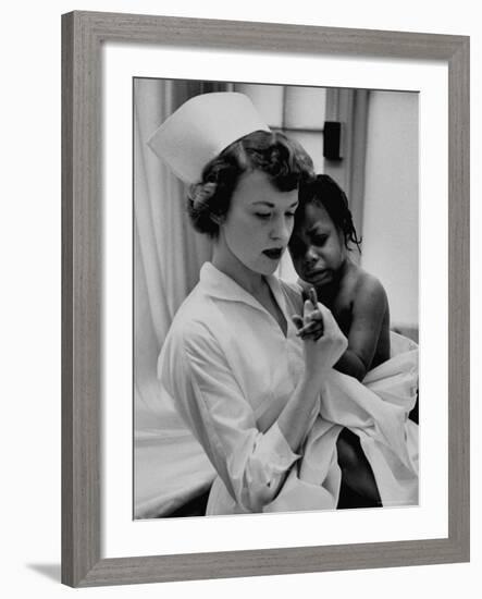 Nurse Holding African American Girl in Her Arms, Examining Her Finger-John Dominis-Framed Photographic Print