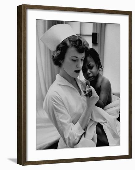 Nurse Holding African American Girl in Her Arms, Examining Her Finger-John Dominis-Framed Photographic Print