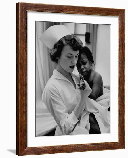 Nurse Holding African American Girl in Her Arms, Examining Her Finger-John Dominis-Framed Photographic Print