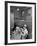 Nurse Sitting at Table with Medical Supplies While Doctors Examine Patient in Background-Wallace Kirkland-Framed Premium Photographic Print