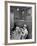 Nurse Sitting at Table with Medical Supplies While Doctors Examine Patient in Background-Wallace Kirkland-Framed Premium Photographic Print