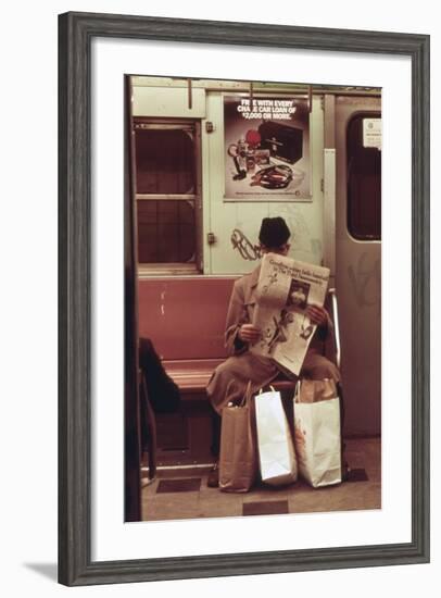 NYC Subway Passenger Reading Newspaper with Shopping Bags in May 1973-null-Framed Photo