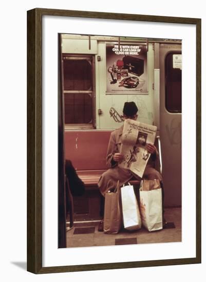 NYC Subway Passenger Reading Newspaper with Shopping Bags in May 1973-null-Framed Photo