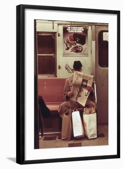 NYC Subway Passenger Reading Newspaper with Shopping Bags in May 1973-null-Framed Photo