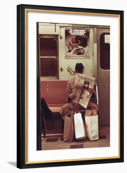 NYC Subway Passenger Reading Newspaper with Shopping Bags in May 1973-null-Framed Photo