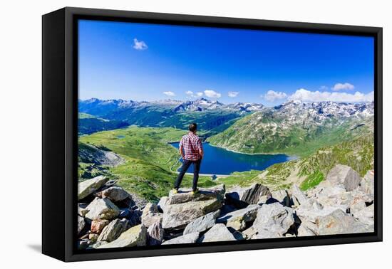 One man looking at the alpine lake of Montespluga standing on rocks, Madesimo-Roberto Moiola-Framed Premier Image Canvas