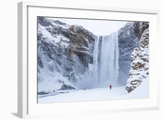 One Person in Red Jacket Walking in the Snow Towards Skogafoss Waterfall in Winter-Neale Clark-Framed Photographic Print