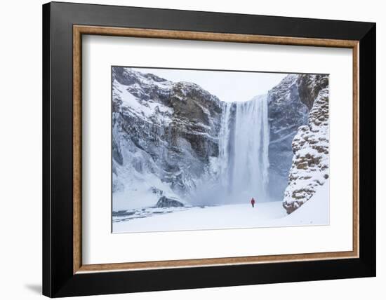 One Person in Red Jacket Walking in the Snow Towards Skogafoss Waterfall in Winter-Neale Clark-Framed Photographic Print