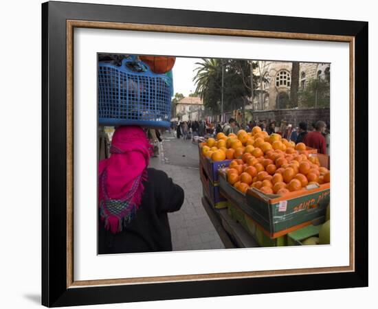 Palestinian Woman in Colourful Scarf and Carrying Bag on Her Head Walking Past an Orange Stall-Eitan Simanor-Framed Photographic Print