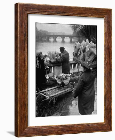 Parisian Flower Vendor at Work Stocking His Stall on the Seine with the Pont Neuf in the Background-Ed Clark-Framed Photographic Print