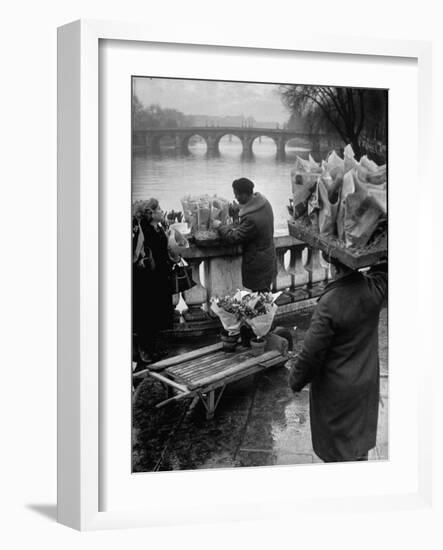 Parisian Flower Vendor at Work Stocking His Stall on the Seine with the Pont Neuf in the Background-Ed Clark-Framed Photographic Print