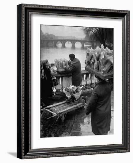 Parisian Flower Vendor at Work Stocking His Stall on the Seine with the Pont Neuf in the Background-Ed Clark-Framed Photographic Print