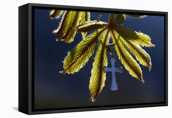 Pendant with cross on a young green chestnut leaf at springtime-null-Framed Premier Image Canvas