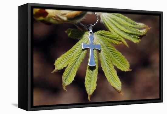 Pendant with cross on a young green chestnut leaf at springtime-null-Framed Premier Image Canvas