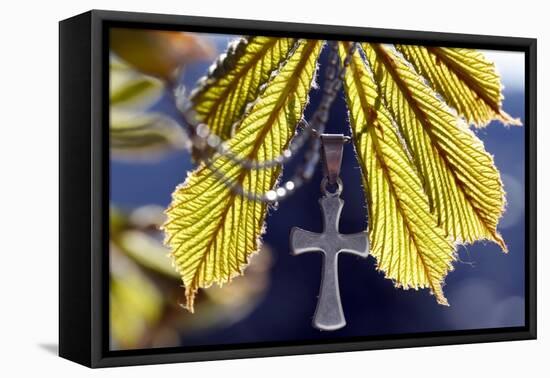 Pendant with cross on a young green chestnut leaf at springtime-null-Framed Premier Image Canvas