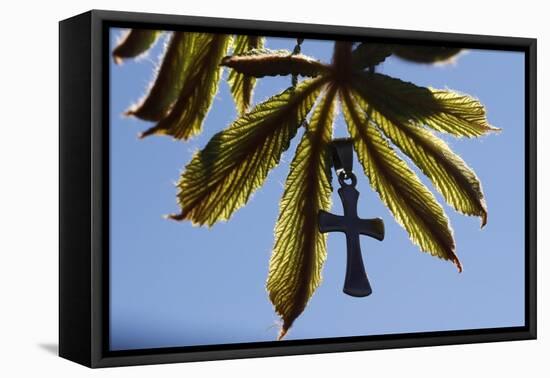 Pendant with cross on a young green chestnut leaf at springtime-null-Framed Premier Image Canvas