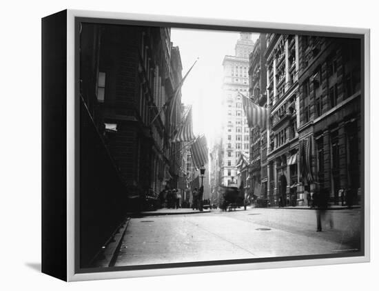 People and Horse Drawn Carts on Wall St, Where American Flags Fly from Buildings-George B^ Brainerd-Framed Premier Image Canvas