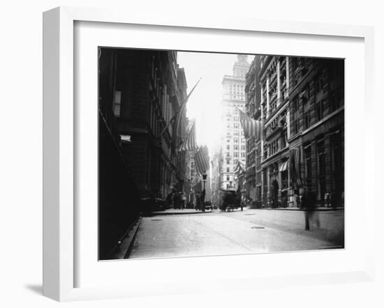 People and Horse Drawn Carts on Wall St, Where American Flags Fly from Buildings-George B^ Brainerd-Framed Photographic Print