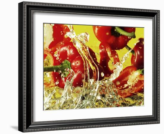 Peppers Falling into Water Against Yellow Background-Michael Meisen-Framed Photographic Print