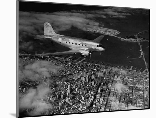 Plane Flying over a City from a Story Concerning United Airlines-Carl Mydans-Mounted Photographic Print